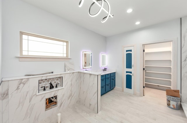 bathroom featuring a marble finish shower, recessed lighting, a spacious closet, vanity, and wood finished floors