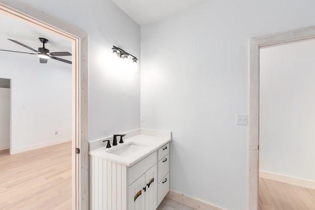 bathroom with a ceiling fan, vanity, baseboards, and wood finished floors