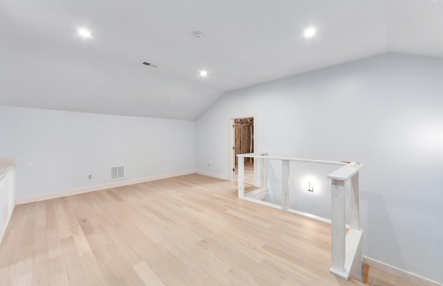 bonus room with lofted ceiling, light wood-style floors, and visible vents