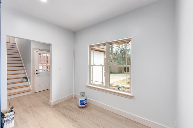 empty room with wood finished floors, baseboards, and stairs