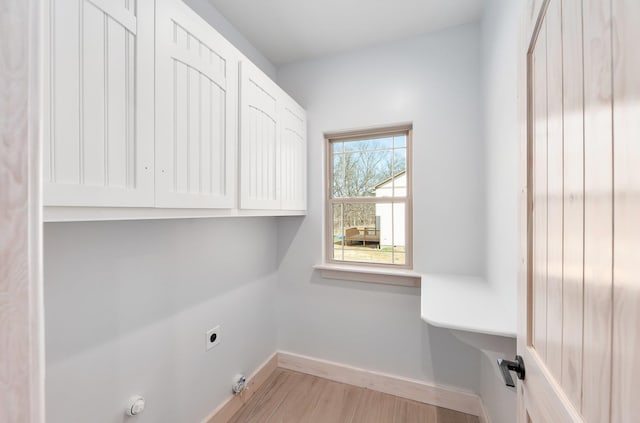 laundry room featuring cabinet space, baseboards, hookup for a gas dryer, light wood-style flooring, and electric dryer hookup