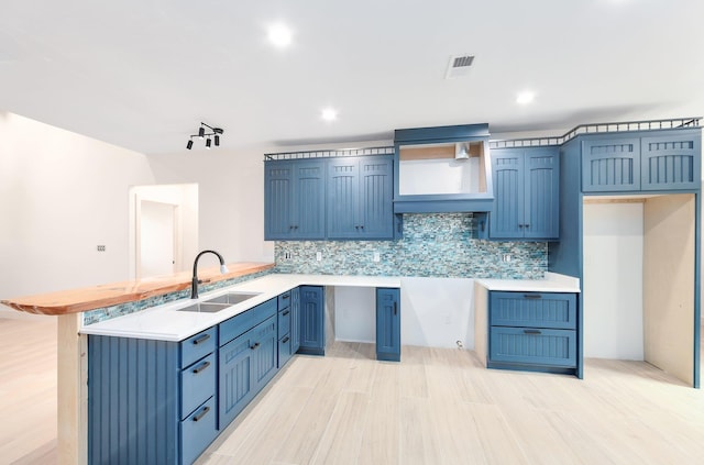 kitchen with a peninsula, backsplash, a sink, and light countertops