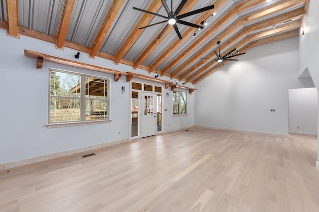 unfurnished living room featuring light wood finished floors, visible vents, a ceiling fan, beamed ceiling, and baseboards