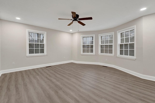 unfurnished room featuring recessed lighting, wood finished floors, visible vents, and baseboards