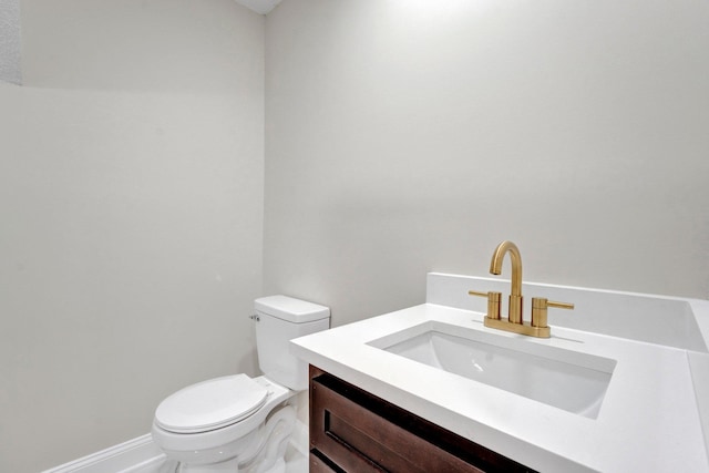 bathroom with toilet, baseboards, and vanity