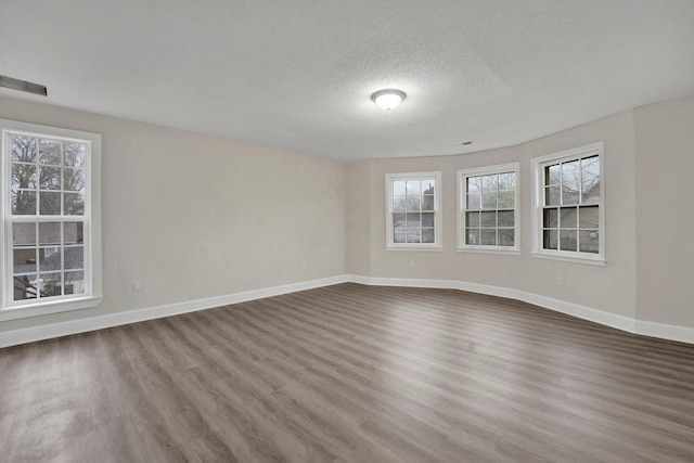 unfurnished room featuring dark wood-style floors, visible vents, baseboards, and a textured ceiling