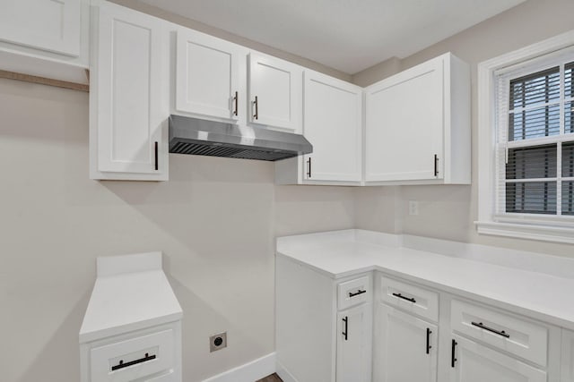 kitchen featuring white cabinets, under cabinet range hood, baseboards, and light countertops