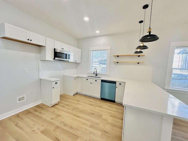 kitchen featuring plenty of natural light, appliances with stainless steel finishes, a peninsula, light wood-style floors, and a sink