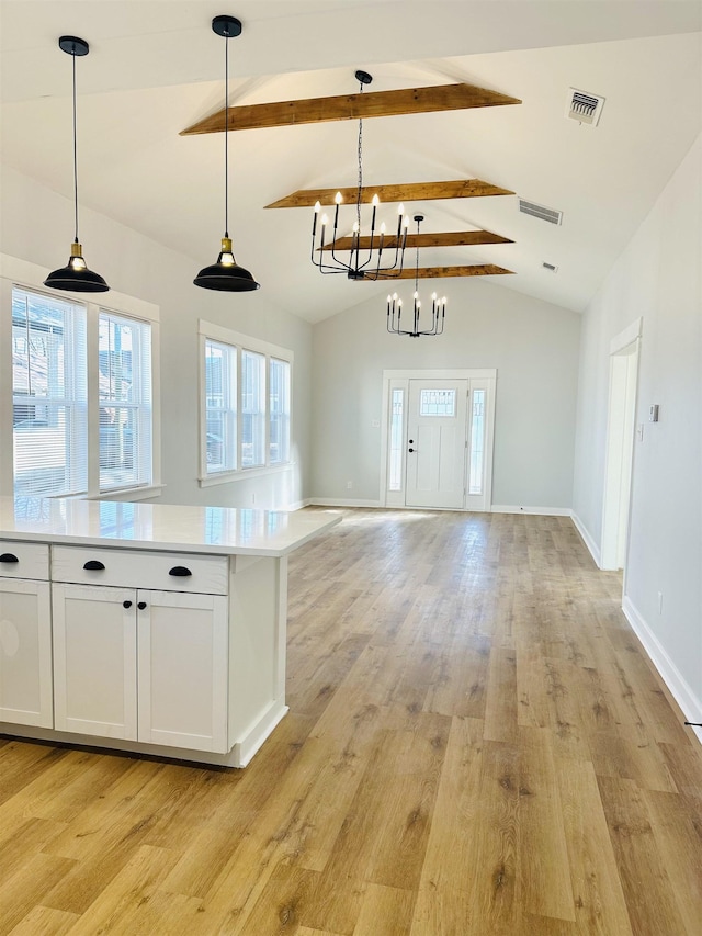 kitchen with beam ceiling, light wood finished floors, light countertops, visible vents, and open floor plan