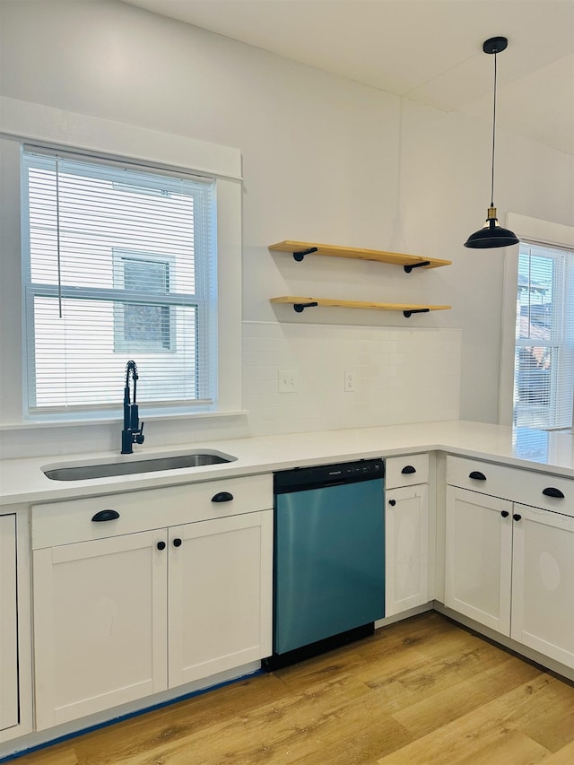 kitchen featuring light wood-style flooring, a sink, white cabinetry, dishwasher, and decorative light fixtures