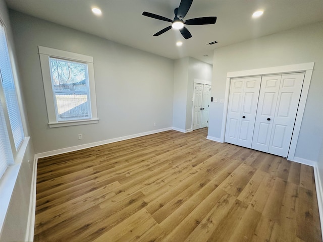 unfurnished bedroom featuring recessed lighting, two closets, baseboards, and wood finished floors