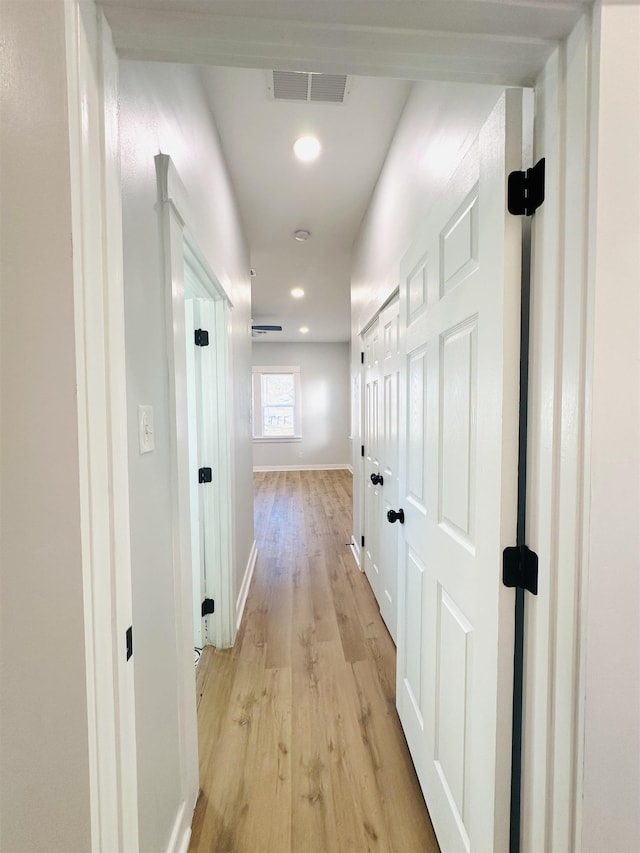 corridor with light wood finished floors, recessed lighting, visible vents, and baseboards