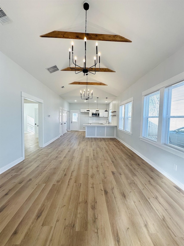 unfurnished living room with light wood-style flooring, a notable chandelier, visible vents, baseboards, and vaulted ceiling