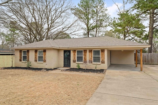 single story home featuring brick siding, roof with shingles, concrete driveway, fence, and an attached carport