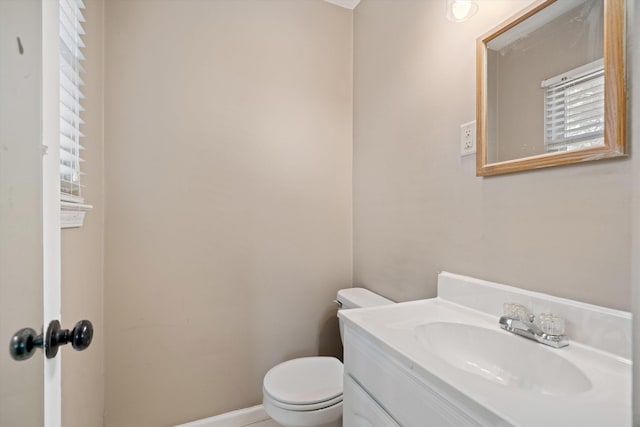 half bath with vanity, toilet, and baseboards