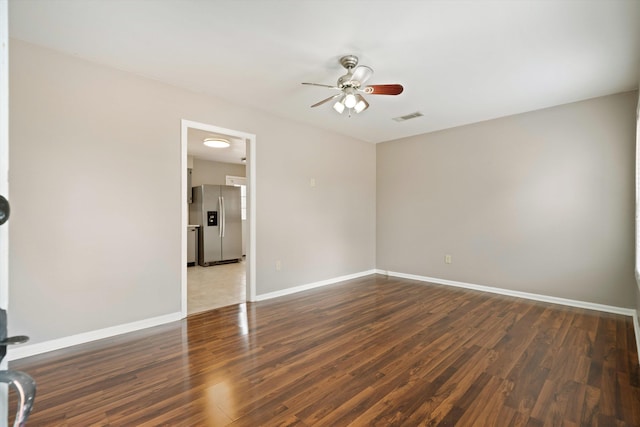 empty room featuring a ceiling fan, visible vents, baseboards, and wood finished floors