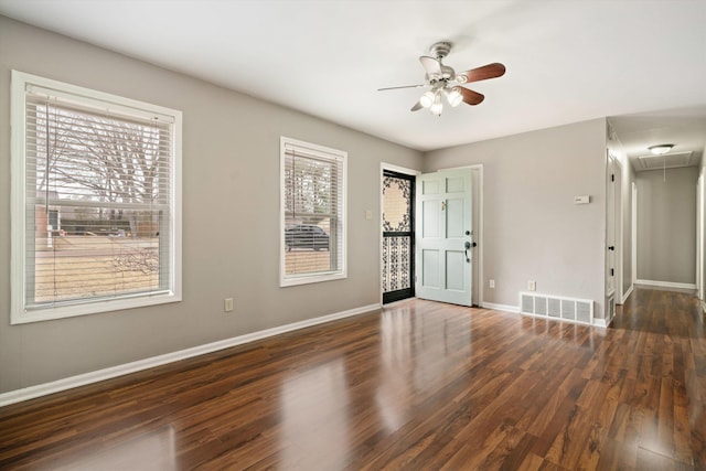 empty room featuring ceiling fan, wood finished floors, visible vents, baseboards, and attic access