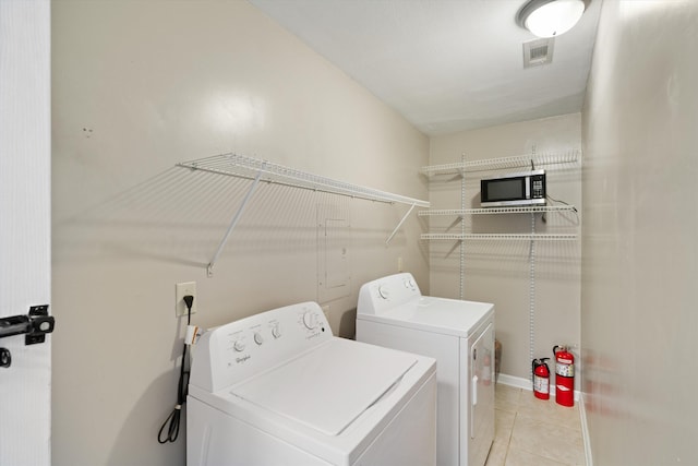 washroom featuring laundry area, washing machine and dryer, visible vents, and light tile patterned flooring