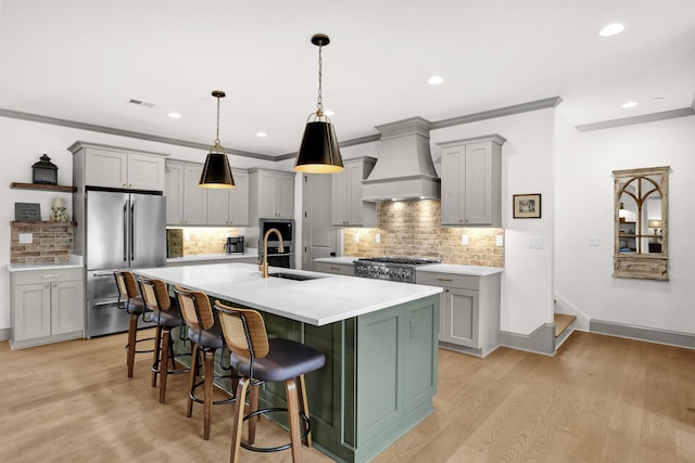 kitchen with visible vents, high quality fridge, custom range hood, gray cabinetry, and a sink