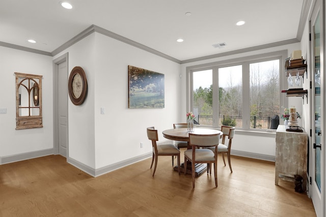 dining area with light wood-style floors, visible vents, and ornamental molding