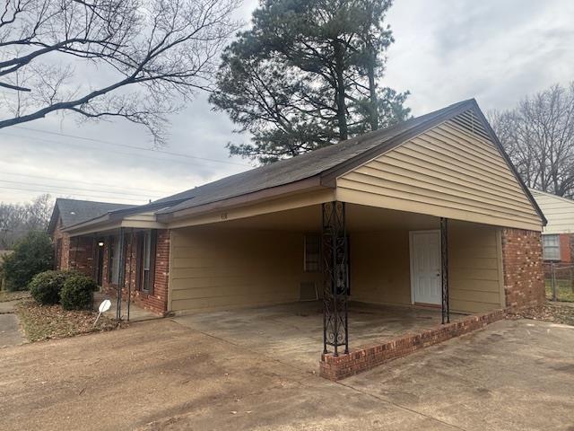 view of property exterior with concrete driveway, brick siding, and an attached carport