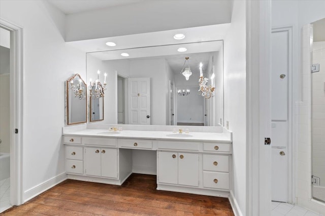 full bathroom featuring a shower with shower door, wood finished floors, a sink, baseboards, and double vanity