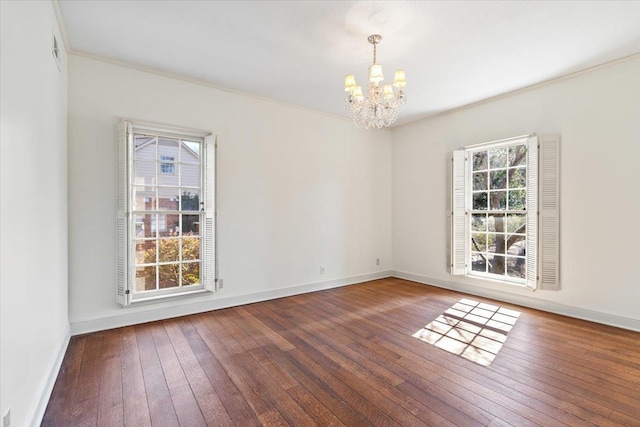 unfurnished room featuring an inviting chandelier, baseboards, and hardwood / wood-style floors