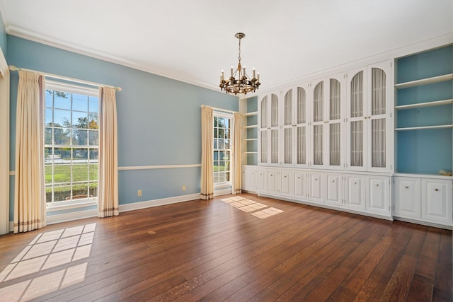 unfurnished room featuring a chandelier, hardwood / wood-style floors, crown molding, and baseboards