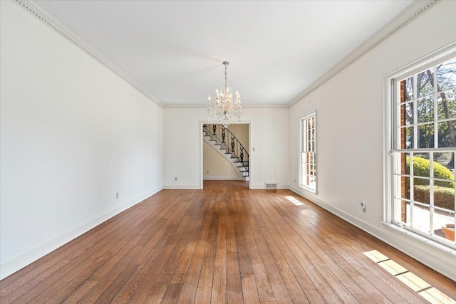 spare room with a wealth of natural light, a notable chandelier, and hardwood / wood-style floors