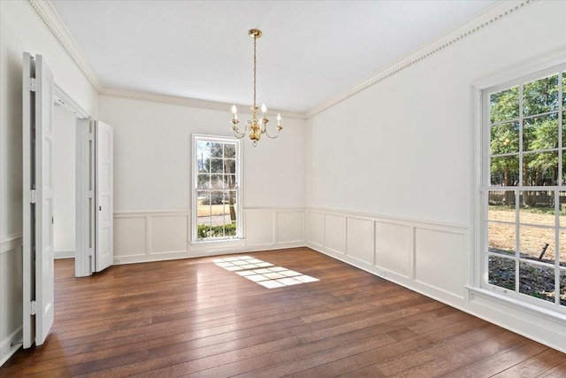 unfurnished dining area with a chandelier, a decorative wall, a wainscoted wall, ornamental molding, and dark wood finished floors