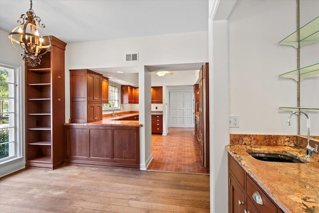 interior space featuring light stone counters, light wood finished floors, visible vents, a healthy amount of sunlight, and a sink