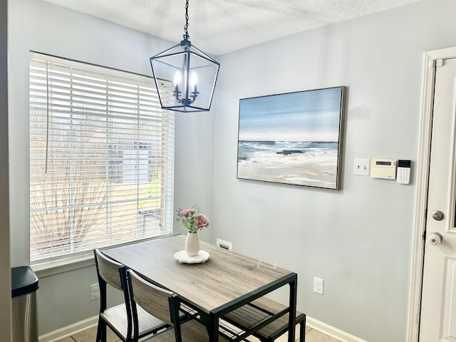 dining room with a textured ceiling, baseboards, and an inviting chandelier