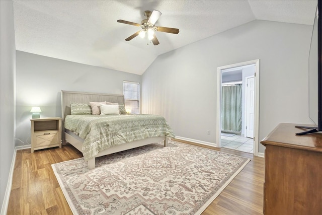 bedroom with lofted ceiling, a textured ceiling, and wood finished floors