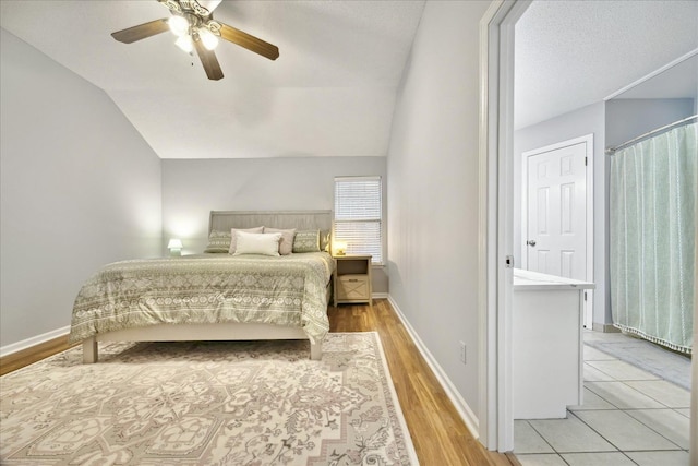 bedroom with vaulted ceiling, a ceiling fan, light wood-style flooring, and baseboards