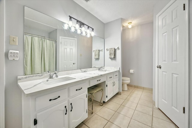 bathroom featuring double vanity, a sink, toilet, and tile patterned floors