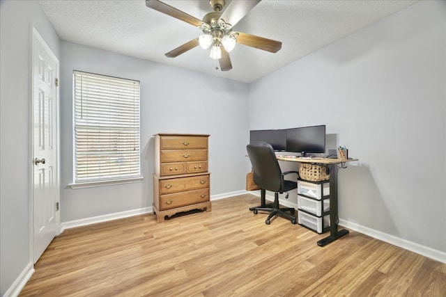 office featuring light wood-type flooring, a ceiling fan, baseboards, and a textured ceiling