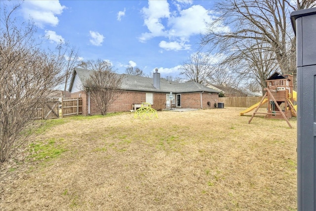 view of yard with a playground, a fenced backyard, and a gate