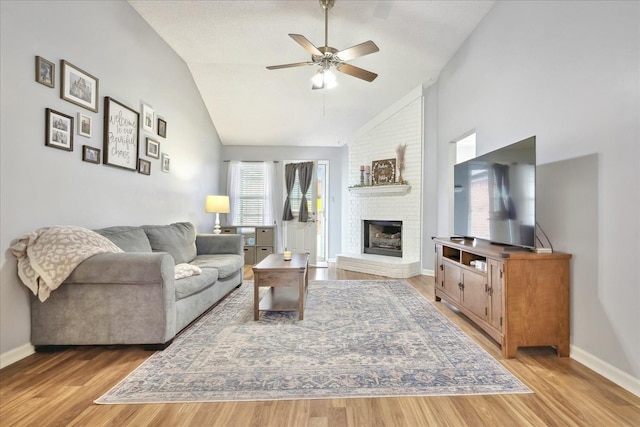 living area featuring a brick fireplace, light wood-style flooring, baseboards, and ceiling fan