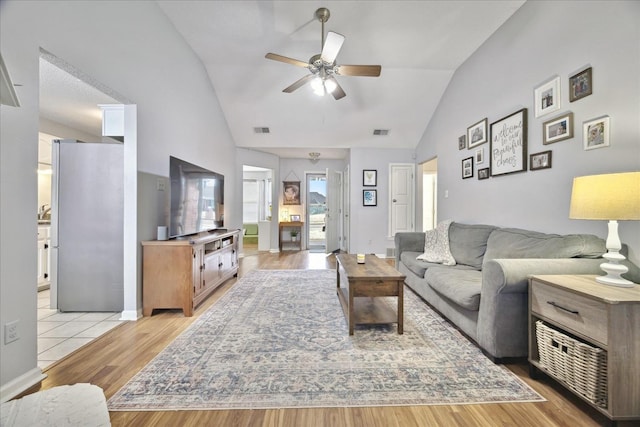 living area featuring light wood-type flooring, visible vents, vaulted ceiling, and ceiling fan