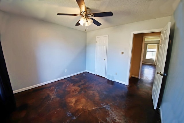 unfurnished bedroom featuring visible vents, a textured ceiling, baseboards, concrete flooring, and ceiling fan