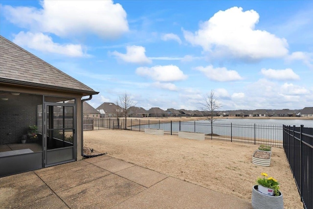 view of patio featuring a water view and fence