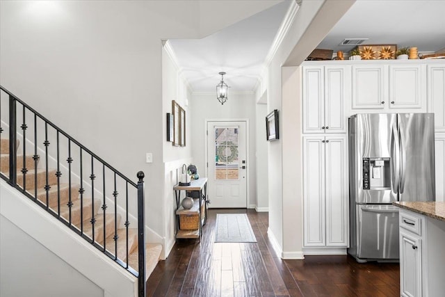 interior space featuring visible vents, baseboards, stainless steel fridge with ice dispenser, dark wood-style floors, and crown molding