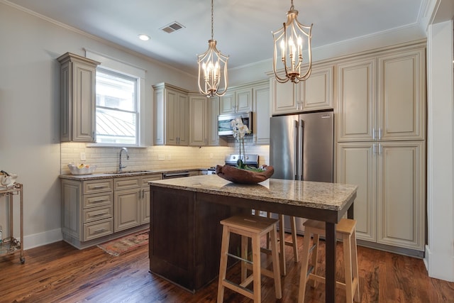 kitchen with visible vents, dark wood-style floors, stainless steel appliances, cream cabinetry, and a sink