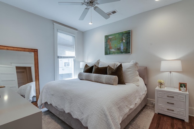 bedroom featuring dark wood-style floors, ceiling fan, visible vents, and baseboards