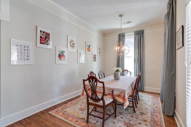 dining area featuring visible vents, ornamental molding, wood finished floors, a chandelier, and baseboards