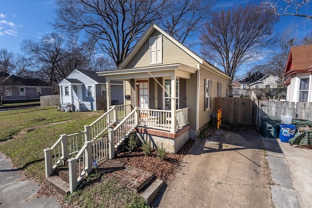 view of front of property with covered porch, fence, and a front yard