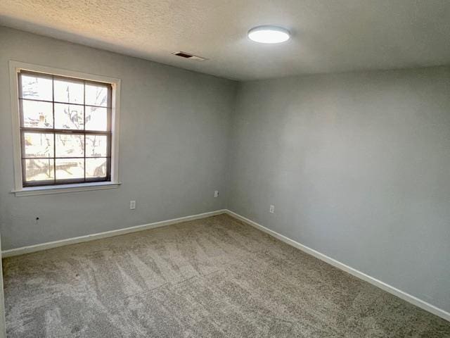 carpeted empty room featuring visible vents, baseboards, and a textured ceiling