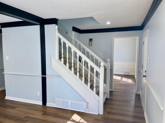 stairs featuring wood finished floors, visible vents, and a decorative wall