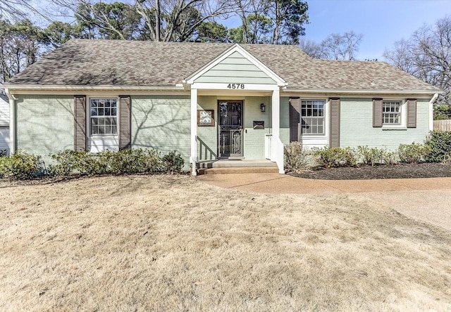 ranch-style home with roof with shingles and brick siding