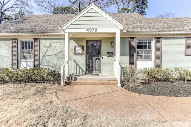 view of front of property with brick siding and roof with shingles